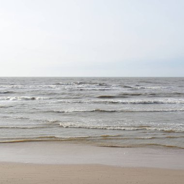 Gün batımında Baltık kıyısı. Yumuşak güneş ışığı, parlayan bulutlar, dalgalar ve su fışkıran berrak gökyüzü. Idyllic deniz manzarası. Hava, iklim değişikliği, doğa
