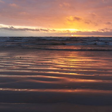 Fırtınadan sonra gün batımında Baltık Denizi. Dramatik gökyüzü, parlayan bulutlar, dofty altın güneş ışığı, dalgalar, fışkıran su. Resimli panoramik manzara. Doğa, çevre, ekoloji