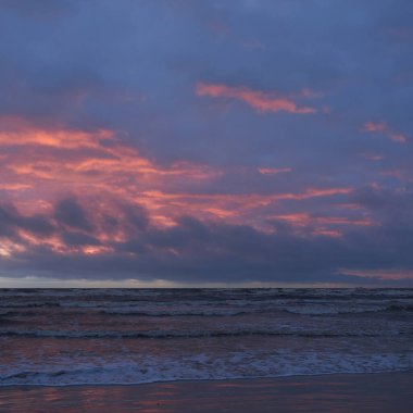 Fırtınadan sonra gün batımında Baltık Denizi. Dramatik gökyüzü, parlayan bulutlar, dofty altın güneş ışığı, dalgalar, fışkıran su. Resimli panoramik manzara. Doğa, çevre, ekoloji