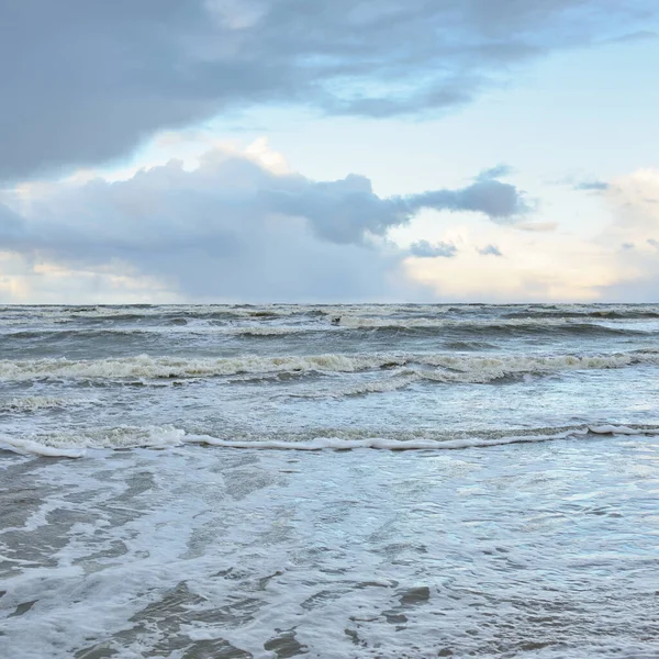 Fırtınadan sonra Baltık Denizi. Dramatik gökyüzü, parlayan bulutlar, yumuşak güneş ışığı. Dalgalar, su sıçratma. Resimli manzara, deniz manzarası, doğa. Panoramik görünüm