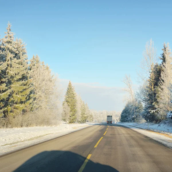 Karla kaplı orman ve kırsal alanda boş otoyol (asfalt yol). Kar sürükleniyor. Avrupa. Doğa, Noel tatilleri, uzak yerler, kış lastikleri, tehlikeli sürüş konsepti