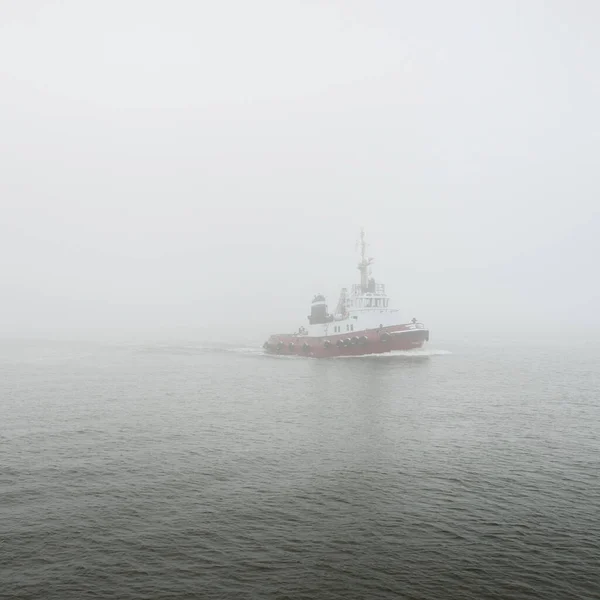 Tug boat in a thick fog. Baltic sea. Winter seascape. Freight transportation, nautical vessel, logistics, industry, commerce, economy