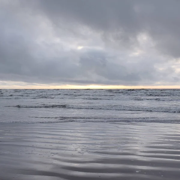 Fırtınadan sonra Baltık Denizi. Yumuşak günbatımı ışığı, çarpıcı parlayan bulutlar. Deniz manzarası, bulutlar, doğa. Sudaki yansımalar. Panoramik manzara. Ekoloji, iklim değişikliği, hava durumu