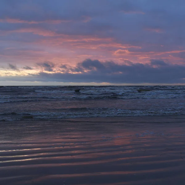 Fırtınadan sonra gün batımında Baltık Denizi. Dramatik gökyüzü, parlayan bulutlar, dofty altın güneş ışığı, dalgalar, fışkıran su. Resimli panoramik manzara. Doğa, çevre, ekoloji