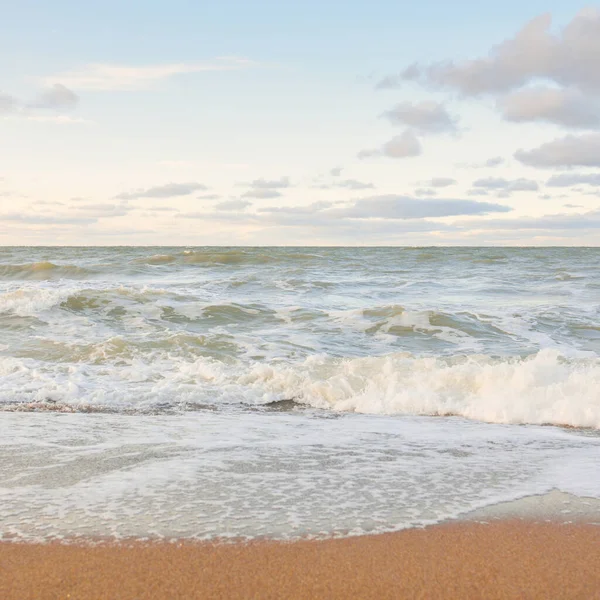 Gün batımında Baltık kıyıları (kum tepeleri). Yumuşak güneş ışığı, parlayan bulutlar, dalgalar ve su fışkıran berrak gökyüzü. Idyllic deniz manzarası. Liepaja, Letonya, Avrupa. Sıcak kış havası, iklim değişikliği, doğa