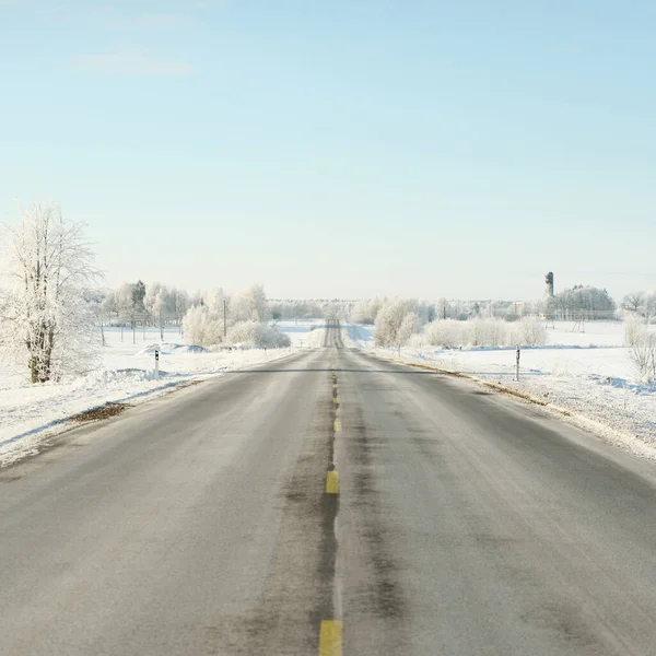 Karla kaplı orman ve kırsal alanda boş otoyol (asfalt yol). Kar sürükleniyor. Avrupa. Doğa, Noel tatilleri, uzak yerler, kış lastikleri, tehlikeli sürüş konsepti