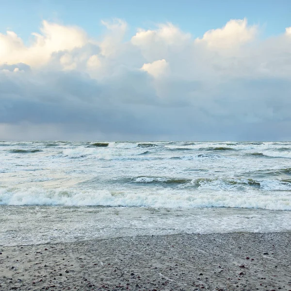 Fırtınadan sonra Baltık Denizi. Dramatik gökyüzü, parlayan bulutlar, yumuşak güneş ışığı. Dalgalar, su sıçratma. Resimli manzara, deniz manzarası, doğa. Panoramik görünüm