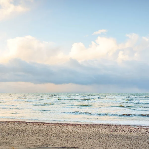 Fırtınadan sonra Baltık Denizi. Dramatik gökyüzü, parlayan bulutlar, yumuşak güneş ışığı. Dalgalar, su sıçratma. Resimli manzara, deniz manzarası, doğa. Panoramik görünüm