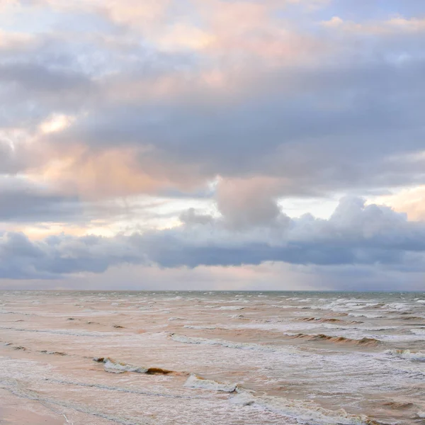 Fırtınadan sonra Baltık Denizi. Dramatik gökyüzü, parlayan bulutlar, yumuşak güneş ışığı. Dalgalar, su sıçratma. Resimli manzara, deniz manzarası, doğa. Panoramik görünüm