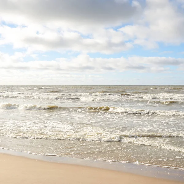 Fırtınadan sonra Baltık Denizi. Dramatik gökyüzü, parlayan bulutlar, yumuşak güneş ışığı. Dalgalar, su sıçratma. Resimli manzara, deniz manzarası, doğa. Panoramik görünüm