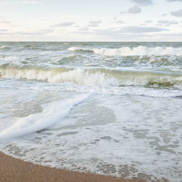 Gün batımında Baltık kıyıları (kum tepeleri). Yumuşak güneş ışığı, parlayan bulutlar, dalgalar ve su fışkıran berrak gökyüzü. Idyllic deniz manzarası. Liepaja, Letonya, Avrupa. Sıcak kış havası, iklim değişikliği, doğa