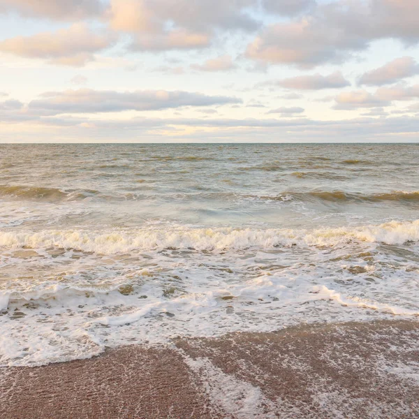 Gün batımında Baltık kıyıları (kum tepeleri). Yumuşak güneş ışığı, parlayan bulutlar, dalgalar ve su fışkıran berrak gökyüzü. Idyllic deniz manzarası. Liepaja, Letonya, Avrupa. Sıcak kış havası, iklim değişikliği, doğa