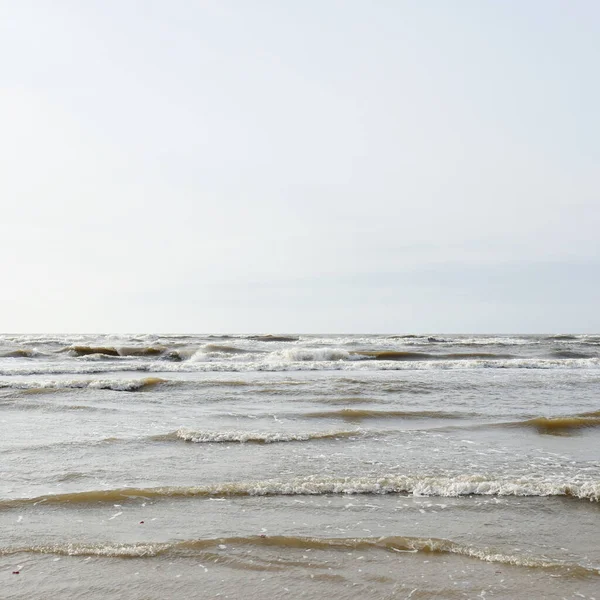 Gün batımında Baltık kıyısı. Yumuşak güneş ışığı, parlayan bulutlar, dalgalar ve su fışkıran berrak gökyüzü. Idyllic deniz manzarası. Hava, iklim değişikliği, doğa