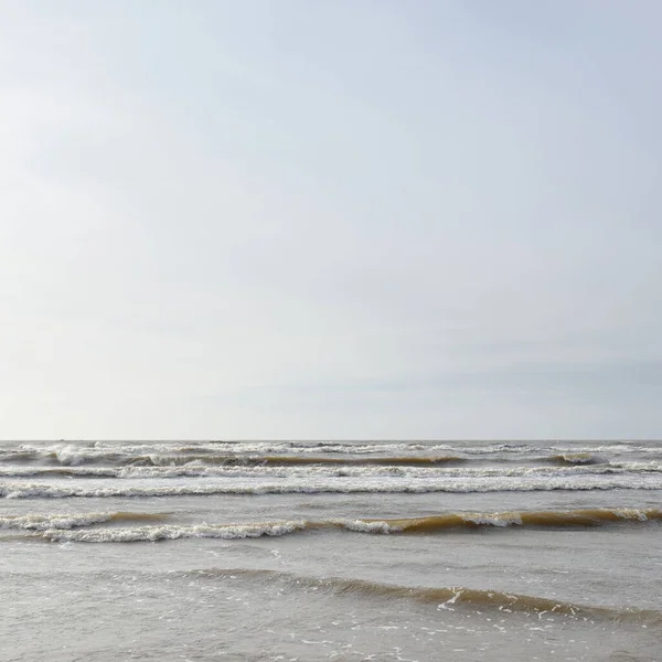 Gün batımında Baltık kıyısı. Yumuşak güneş ışığı, parlayan bulutlar, dalgalar ve su fışkıran berrak gökyüzü. Idyllic deniz manzarası. Hava, iklim değişikliği, doğa