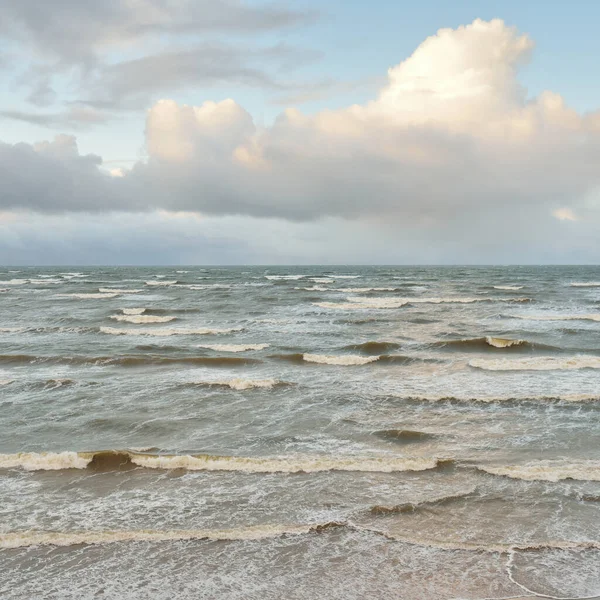 Fırtınadan sonra Baltık Denizi. Dramatik gökyüzü, parlayan bulutlar, yumuşak güneş ışığı. Dalgalar, su sıçratma. Resimli manzara, deniz manzarası, doğa. Panoramik görünüm