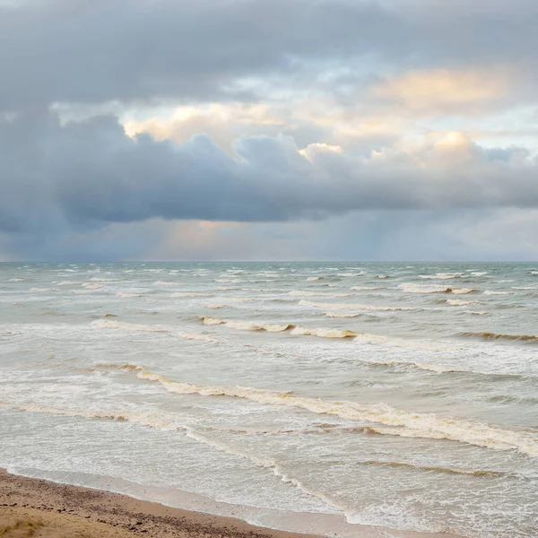Fırtınadan sonra Baltık Denizi. Dramatik gökyüzü, parlayan bulutlar, yumuşak güneş ışığı. Dalgalar, su sıçratma. Resimli manzara, deniz manzarası, doğa. Panoramik görünüm