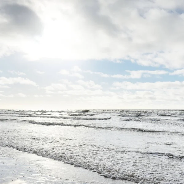 Fırtınadan sonra Baltık Denizi. Dramatik gökyüzü, parlayan bulutlar, yumuşak güneş ışığı. Dalgalar, su sıçratma. Resimli manzara, deniz manzarası, doğa. Panoramik görünüm