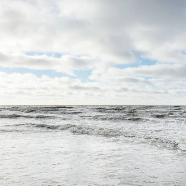 Fırtınadan sonra Baltık Denizi. Dramatik gökyüzü, parlayan bulutlar, yumuşak güneş ışığı. Dalgalar, su sıçratma. Resimli manzara, deniz manzarası, doğa. Panoramik görünüm