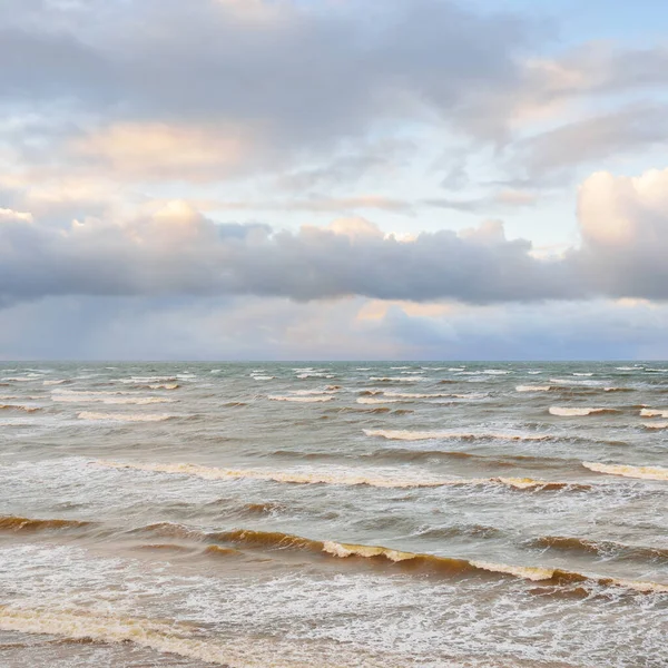 Fırtınadan sonra Baltık Denizi. Dramatik gökyüzü, parlayan bulutlar, yumuşak güneş ışığı. Dalgalar, su sıçratma. Resimli manzara, deniz manzarası, doğa. Panoramik görünüm