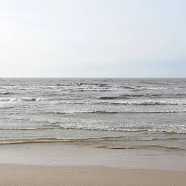 Gün batımında Baltık kıyısı. Yumuşak güneş ışığı, parlayan bulutlar, dalgalar ve su fışkıran berrak gökyüzü. Idyllic deniz manzarası. Hava, iklim değişikliği, doğa