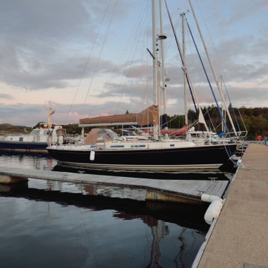 Günbatımında yat limanında demirlemiş zarif ve modern yelkenliler. Dramatik bulutlar. Inner Hebrides, İskoçya, İngiltere. Ulaşım, spor, yelkencilik, eğlence, eğlence, eğlence, gezi, turizm