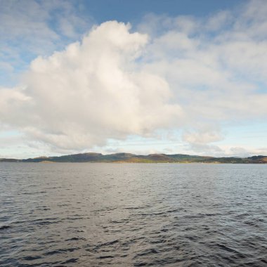 İskoçya, Rothesay 'ın kayalık kıyıları, tepeleri ve vadileri üzerinde dramatik bir gökyüzü. Yelkenliden panoramik manzara. Seyahat merkezleri, turizm, yürüyüş, dönüm noktası, ekoloji, çevre, doğa temaları