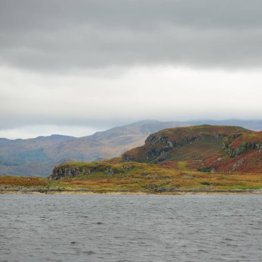 İskoçya, Rothesay 'ın kayalık kıyıları, tepeleri ve vadileri üzerinde dramatik bir gökyüzü. Yelkenliden panoramik manzara. Seyahat merkezleri, turizm, yürüyüş, dönüm noktası, ekoloji, çevre, doğa temaları