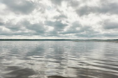 Kristal berrak bir orman gölü (nehir) kıyısından panoramik manzara. Dramatik gökyüzü, parlayan fırtına bulutları. Idyllic manzara. İlkbahar, yazın başı. Doğa, çevre, ekoloji, eko-turizm, yürüyüş