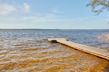 Orman nehri (göl) güneşli bir günde. Ahşap iskele. Clea gökyüzü, kristal berrak suda yansıyor. Idyllic manzara, kırsal manzara. Doğa, ekoloji, eko-turizm, yürüyüş, ekoloji beldesi, yerel turizm