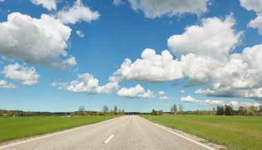 Tarla ve orman boyunca (yeni asfalt yolu) boş bir otoyol. Yağmurdan önce dramatik fırtına bulutları. Turizm, yol gezisi, özgürlük, tatiller, lojistik, uzak yerler kavramları