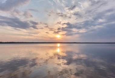Gün batımında Orman Gölü. Yumuşak güneş ışığı, parlayan pembe ve altın bulutlar, kristal berrak bir suda yansıma. Idyllic manzara. Panoramik manzara. Doğa, ekoloji, çevrecilik. Barış ve neşe kavramları