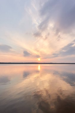 Gün batımında Orman Gölü. Yumuşak güneş ışığı, parlayan pembe ve altın bulutlar, kristal berrak bir suda yansıma. Idyllic manzara. Panoramik manzara. Doğa, ekoloji, çevrecilik. Barış ve neşe kavramları