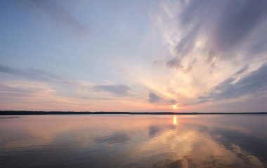 Gün batımında Orman Gölü. Yumuşak güneş ışığı, parlayan pembe ve altın bulutlar, kristal berrak bir suda yansıma. Idyllic manzara. Panoramik manzara. Doğa, ekoloji, çevrecilik. Barış ve neşe kavramları