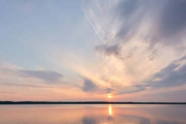 Gün batımında Orman Gölü. Yumuşak güneş ışığı, parlayan pembe ve altın bulutlar, kristal berrak bir suda yansıma. Idyllic manzara. Panoramik manzara. Doğa, ekoloji, çevrecilik. Barış ve neşe kavramları