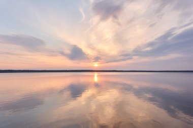 Gün batımında Orman Gölü. Yumuşak güneş ışığı, parlayan pembe ve altın bulutlar, kristal berrak bir suda yansıma. Idyllic manzara. Panoramik manzara. Doğa, ekoloji, çevrecilik. Barış ve neşe kavramları
