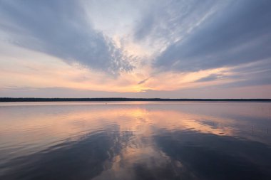 Gün batımında Orman Gölü. Yumuşak güneş ışığı, parlayan pembe ve altın bulutlar, kristal berrak bir suda yansıma. Idyllic manzara. Panoramik manzara. Doğa, ekoloji, çevrecilik. Barış ve neşe kavramları