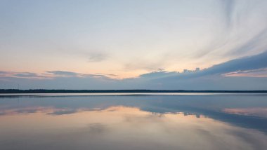Gün batımında Orman Gölü. Yumuşak güneş ışığı, gece yarısı güneşi, parlayan bulutlar, kristal berrak bir suda yansıma. Idyllic manzara. Panoramik manzara. Doğa, ekoloji, çevre turizmi. İlkbahar, yazın başı