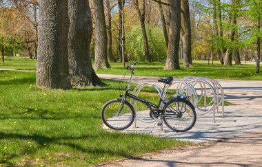 Şehir parkına park etmiş bir bisiklet. İlkbahar, yazın başı. Dinlenme alanı, yürüyüş parkuru. Eğlence, boş zaman aktivitesi. spor, bisiklet, yürüyüş, sağlıklı yaşam tarzı temaları