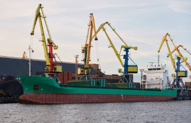 Kargo iskelesine demir atmış büyük bir gemi. Vinçler arka planda. Letonya 'da sızıntı var. Nakliye, endüstri, lojistik, özel ekipman