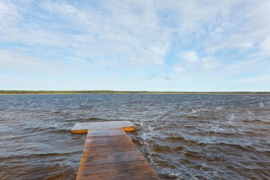 Güneşli bir günde, bir orman gölünde (nehir) bir ada. Sudaki yansımalar. Mavi gökyüzü, parlayan bulutlar. Idyllic manzara. Saf doğa, ekoloji, ekolojik rezerv, eko-turizm.