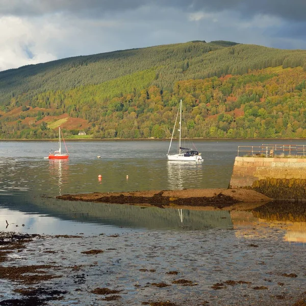 Sailboat anchored in lake. Majestic forest hills. Scotland, UK. Atmospheric landscape. Travel destinations, sailing, cruising, eco tourism, hiking, nature, environmental conservation