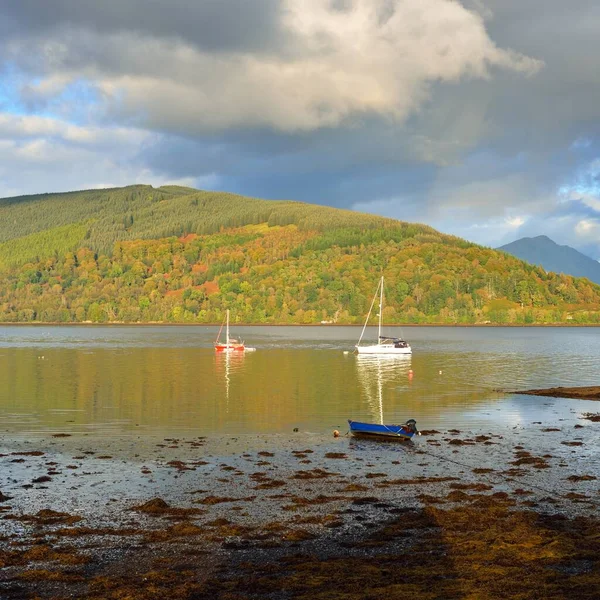 Sailboat anchored in lake. Majestic forest hills. Scotland, UK. Atmospheric landscape. Travel destinations, sailing, cruising, eco tourism, hiking, nature, environmental conservation