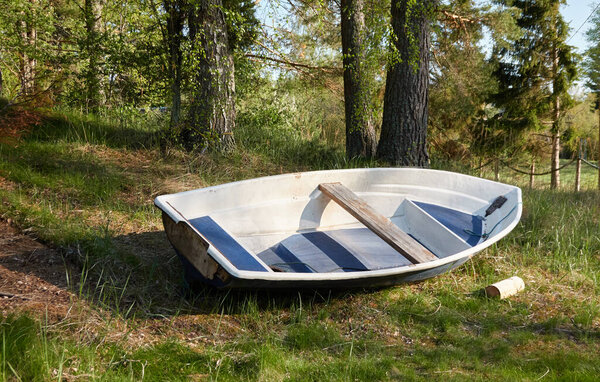 Recreational area and resting zone in a forest park. Irbe river, Kurzeme, Latvia. Small fishing boat standing on land. Nature, ecology, eco tourism, sport, healthy lifestyle, wanderlust