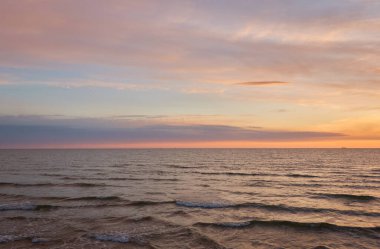 Gün batımında Baltık Denizi. Dramatik gökyüzü, mavi ve pembe parlayan bulutlar, yumuşak altın güneş ışığı, gece yarısı güneşi. Deniz manzarası, bulut manzarası, doğa. Panoramik görünüm