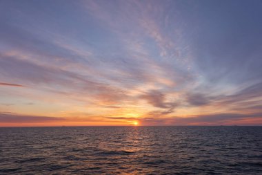 Gün batımında Baltık Denizi. Dramatik gökyüzü, mavi ve pembe parlayan bulutlar, yumuşak altın güneş ışığı, gece yarısı güneşi. Deniz manzarası, bulut manzarası, doğa. Panoramik görünüm
