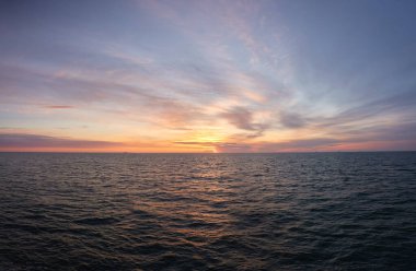 Gün batımında Baltık Denizi. Dramatik gökyüzü, mavi ve pembe parlayan bulutlar, yumuşak altın güneş ışığı, gece yarısı güneşi. Deniz manzarası, bulut manzarası, doğa. Panoramik görünüm