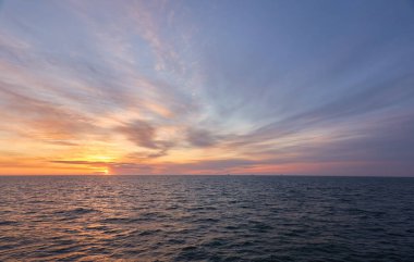 Gün batımında Baltık Denizi. Dramatik gökyüzü, mavi ve pembe parlayan bulutlar, yumuşak altın güneş ışığı, gece yarısı güneşi. Deniz manzarası, bulut manzarası, doğa. Panoramik görünüm