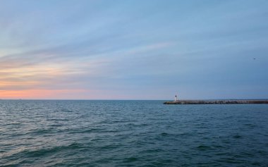 Fırtınadan sonra Baltık Denizi. Deniz fenerine doğru ilerleyin. Dalgalar. Dramatik gökyüzü, bulutlar, gece yarısı güneşi. Resimli rüya gibi deniz manzarası, bulut manzarası. Doğa, seyahat yerleri. Panoramik görünüm