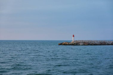 Fırtınadan sonra Baltık Denizi. Deniz fenerine doğru ilerleyin. Dalgalar. Dramatik gökyüzü, bulutlar, gece yarısı güneşi. Resimli rüya gibi deniz manzarası, bulut manzarası. Doğa, seyahat yerleri. Panoramik görünüm