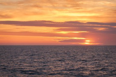 Gün batımında Baltık Denizi. Dramatik gökyüzü, mavi ve pembe parlayan bulutlar, yumuşak altın güneş ışığı, gece yarısı güneşi. Deniz manzarası, bulut manzarası, doğa. Panoramik görünüm